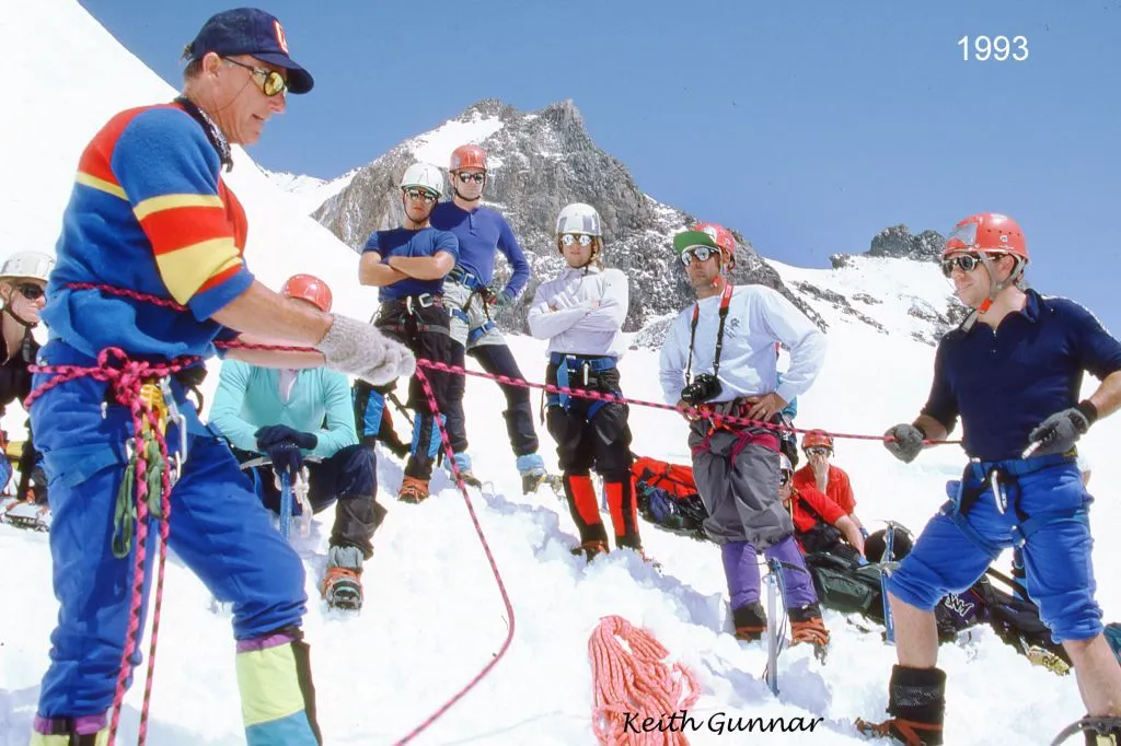 Group of climbers receiving instruction on snowy mountain slope with rocky peaks in 1993.