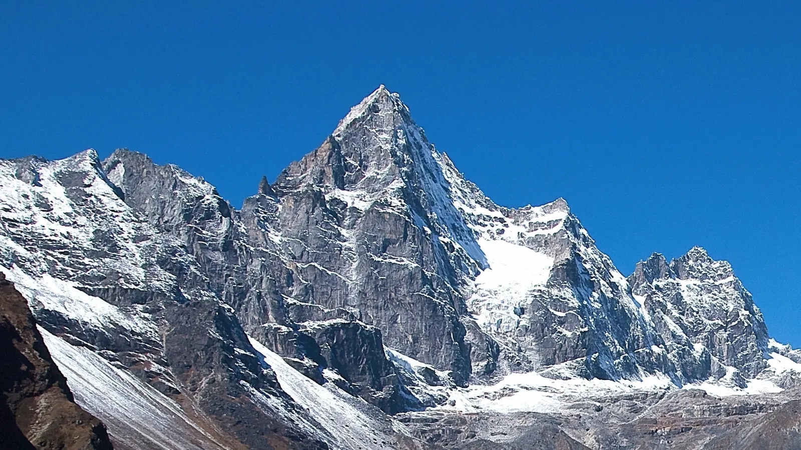 Sharp mountain peak with snow patches under a clear blue sky.