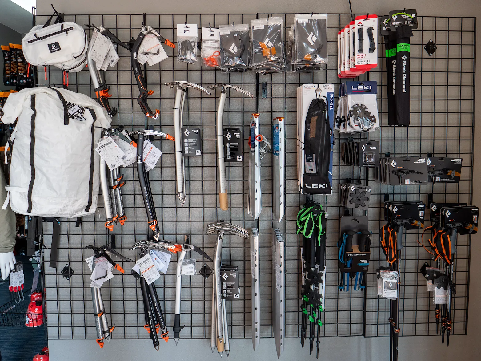 Wall display of hiking and climbing gear including backpacks, ice axes, poles, and gloves.